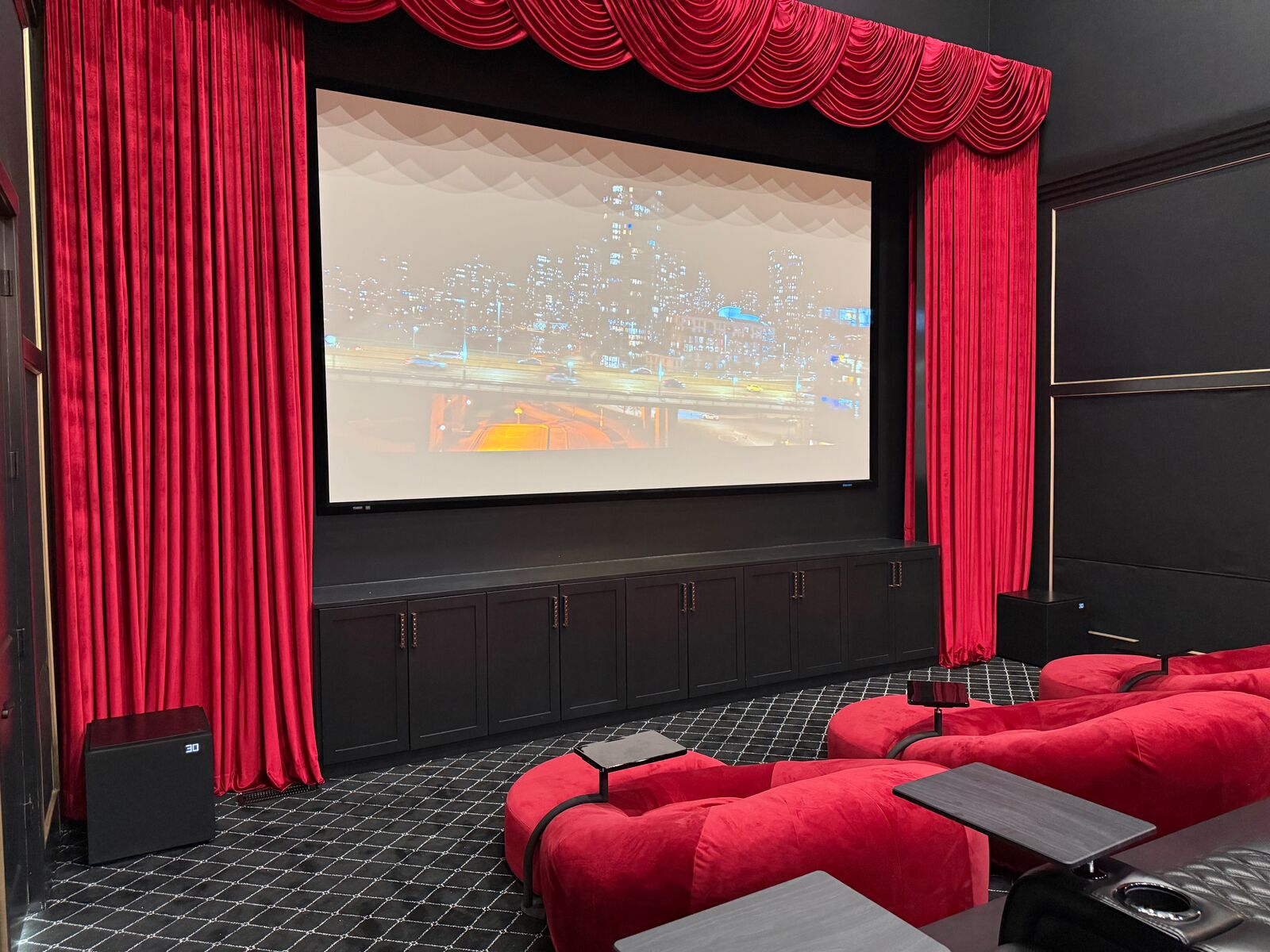 Home cinema with red velvet curtains framing a large screen